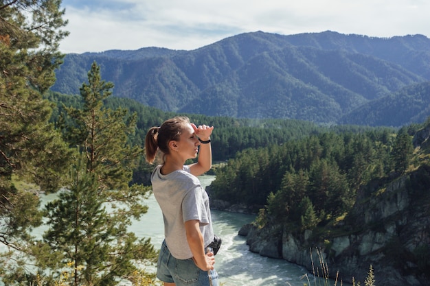 uma jovem aucasiana olha para longe, contra o fundo de uma bela paisagem