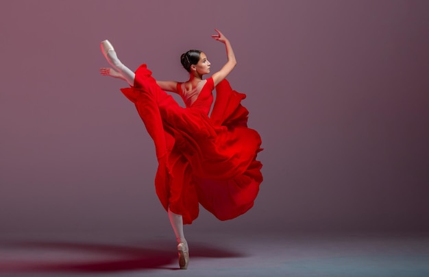 Uma jovem bailarina graciosa vestida com sapatilhas e uma saia vermelha leve demonstra suas habilidades de dança A beleza do balé clássico