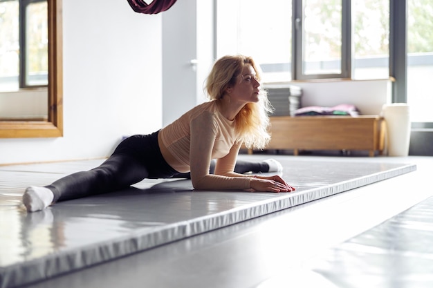 Uma jovem bastante desportiva sentada e fazendo split durante o exercício no estúdio de alongamento Conceito de estilo de vida saudável