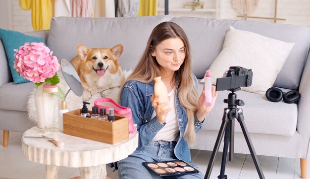 Uma jovem blogueira de beleza grava seu videoblog sobre revisão de beleza de cosméticos ao vivo em casa i ...
