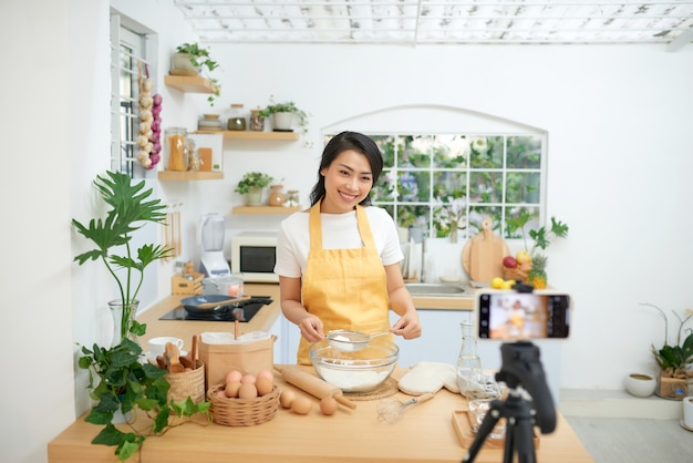 Uma jovem blogueira de culinária asiática trabalhando em um novo vídeo e explicando como cozinhar um prato