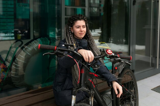 Uma jovem bonita com dreadlocks a andar de bicicleta na cidade.