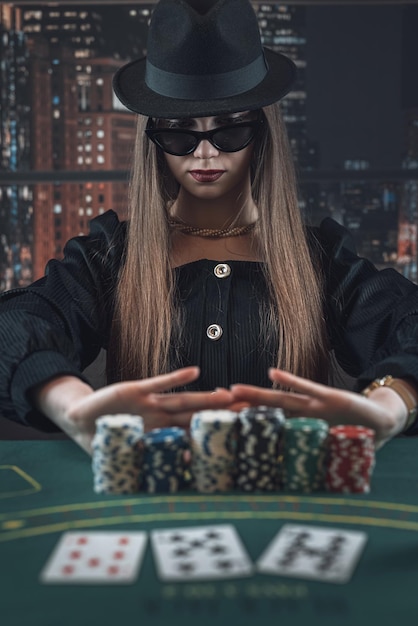Uma jovem bonita com óculos escuros joga póquer com a cara de póquer a falar de sorte e ganhar.