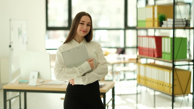 Uma jovem bonita e positiva sorrindo fica no escritório