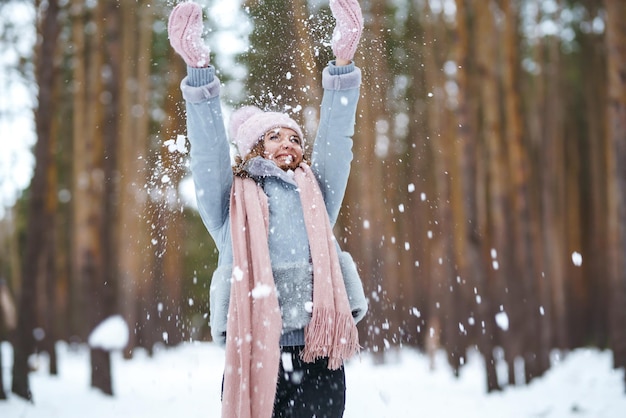 Uma jovem bonita está brincando com neve na floresta Estilo de vida de inverno felicidade emoções natureza