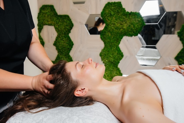 Uma jovem bonita está recebendo uma massagem profissional na cabeça no spa