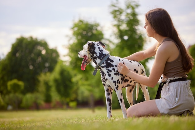 uma jovem brinca com um dálmata no conceito de cuidado de cães do parque