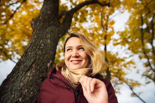 Foto uma jovem brincalhona apreciando as folhas amarelas de outono no parque de outono as pessoas sentem dados sazonais