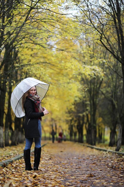 Uma jovem caminhando no parque de outono com um guarda-chuva