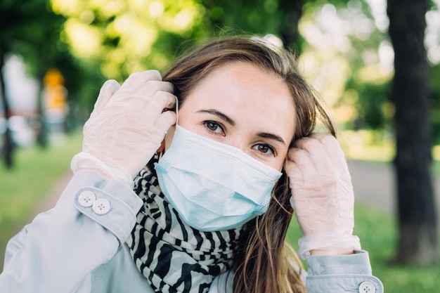 Uma jovem caucasiana foi passear no parque usando luvas médicas e uma máscara