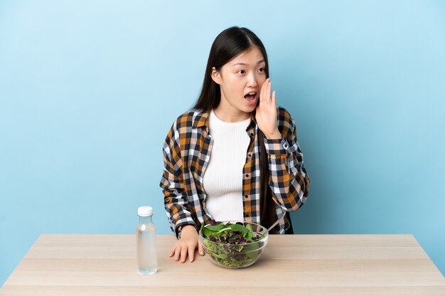 Uma jovem chinesa a comer uma salada a gritar com a boca aberta para o lado