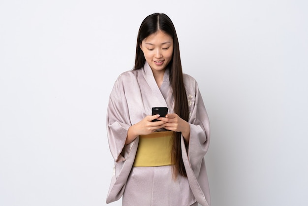 Uma jovem chinesa de quimono a enviar uma mensagem com o telemóvel