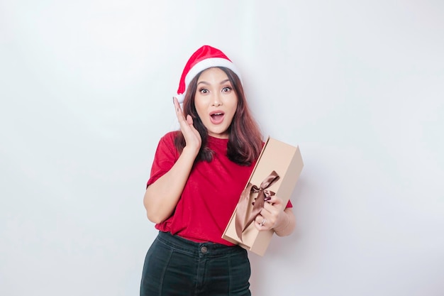 Uma jovem chocada está usando chapéu de Papai Noel39 e segurando presentes de Natal