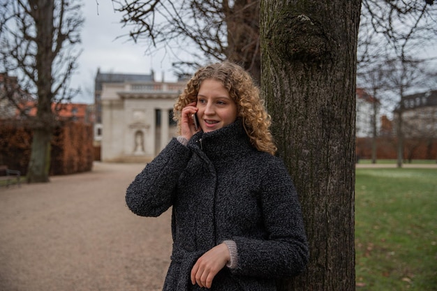 Uma jovem com aparelho faz um telefonema enquanto está em um parque ao ar livre no inverno