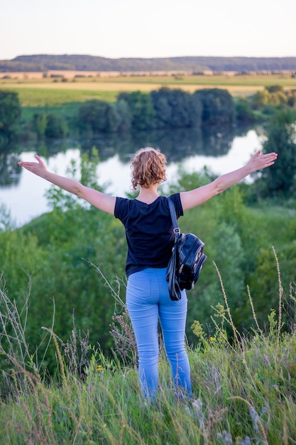 Uma jovem com as mãos levantadas apreciando a unidade com a natureza_