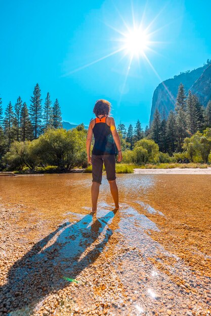 Uma jovem com camiseta preta na água do lago e o sol ao fundo