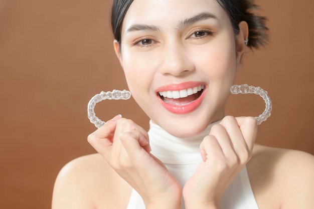 Uma jovem com dentes bonitos está segurando o conceito dental saudável Invisalign