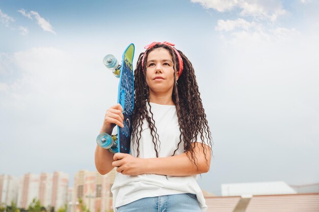 Foto uma jovem com dreadlocks segura um skate e ouve musicgeneration z