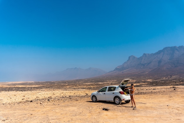 Uma jovem com o carro alugado na praia Cofete do parque natural de Jandia, Barlovento, ao sul de Fuerteventura, nas Ilhas Canárias. Espanha