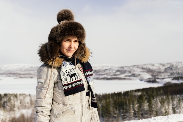 Uma jovem com roupas quentes viaja pelo norte frio, neve branca em todos os lugares