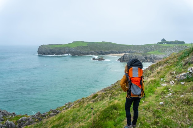 Uma jovem com seu filho caminhando em direção a Playa de Troenzo e Playa de la Tayada na península de Borizu na cidade de Llanes Asturias Espanha