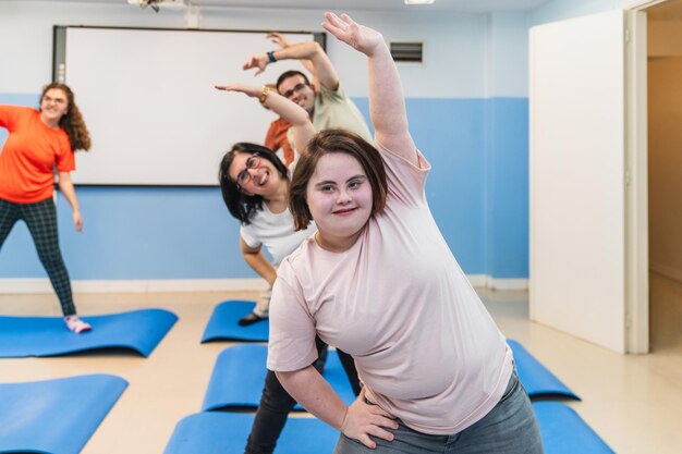 Uma jovem com síndrome de Down faz uma postura alegre de ioga com sua turma