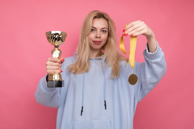 Uma jovem com um casaco elegante segurando uma taça de ouro e medalha