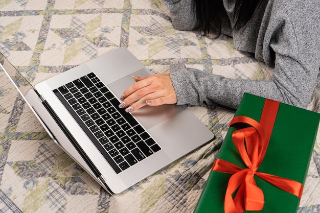Foto uma jovem com um chapéu vermelho de papai noel está sentada em frente a um laptop conceito de compras on-line