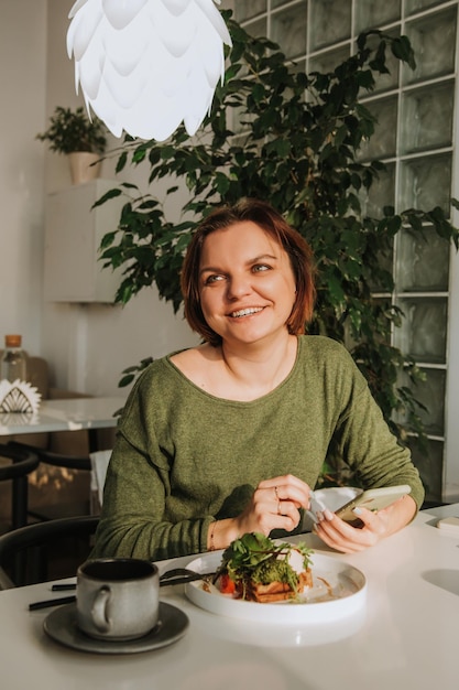 Foto uma jovem com um corte de cabelo curto está sentada em uma mesa em um café