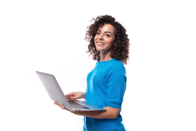 Foto uma jovem com um penteado rizado vestida com uma camiseta azul trabalha em um laptop