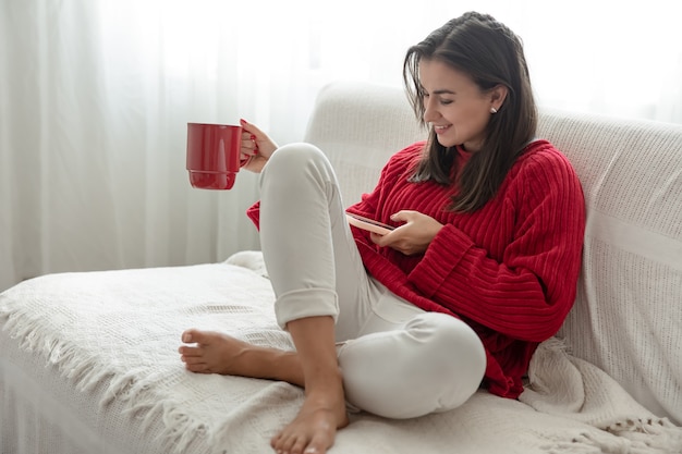 Uma jovem com um suéter vermelho e uma xícara vermelha