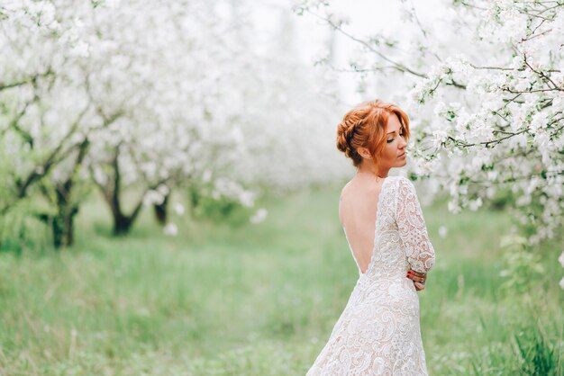 Uma jovem com um vestido branco está em um jardim florido