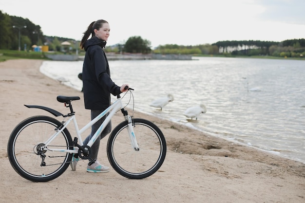 Uma jovem com uma bicicleta no lago