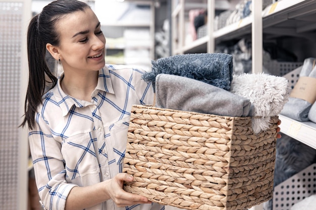 Uma jovem com uma cesta de vime cheia de cobertores em uma loja de melhorias domésticas