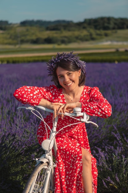 Uma jovem com uma coroa na cabeça senta-se em uma bicicleta em um campo de lavanda