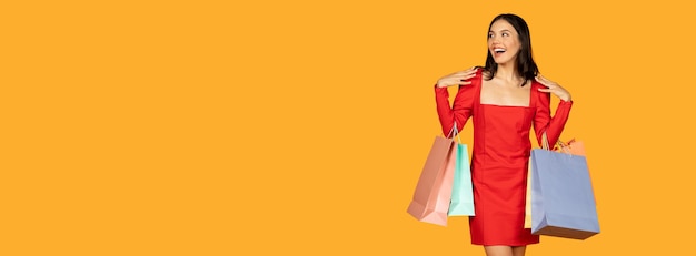 Uma jovem com uma expressão alegre está carregando vários sacos de compras enquanto vestida com um estilo
