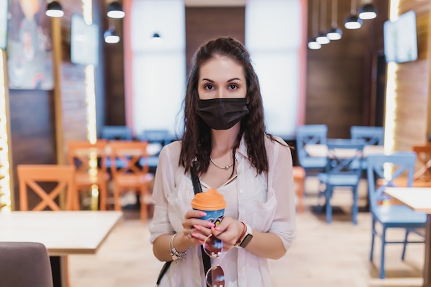 Uma jovem com uma máscara do vírus foi tomar um café. a cidade está em quarentena. alta qualidade