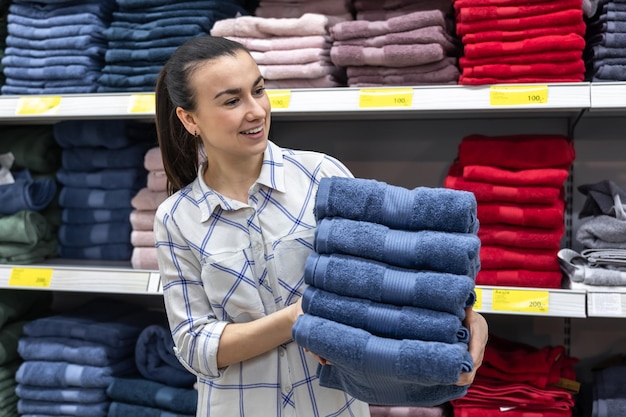 Uma jovem com uma pilha de toalhas em uma loja de melhorias domésticas