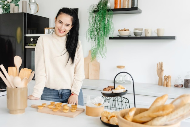 Uma jovem confeiteira sorri e olha para a câmera uma dona de casa em uma cozinha moderna faz um des