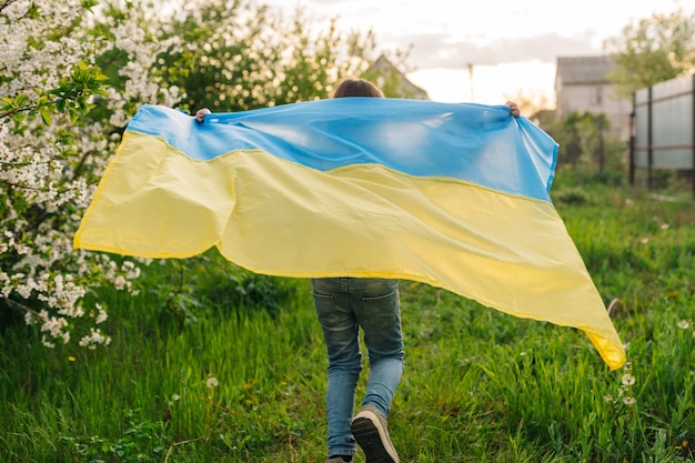 Uma jovem corre com a bandeira ucraniana foto de uma menina correndo com uma bandeira ucraniana usada como capa