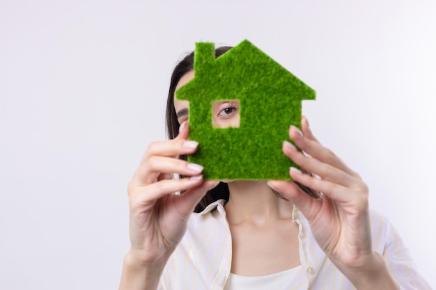 Foto uma jovem corretora de imóveis tem um modelo de uma casa verde em suas mãos venda de imóveis ecológicos