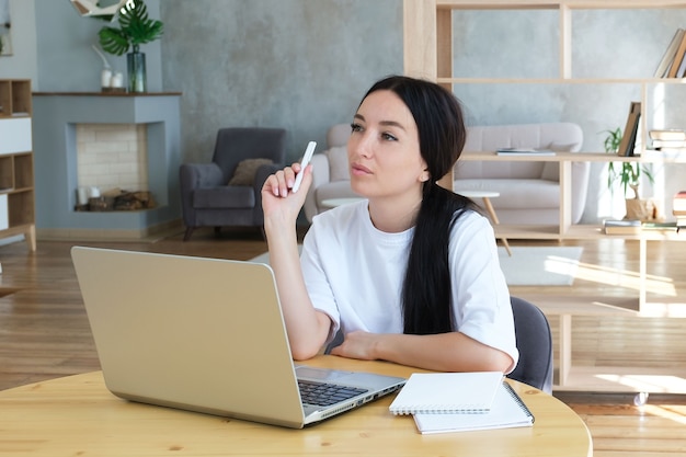 Foto uma jovem cria um plano de negócios enquanto está sentada em um laptop