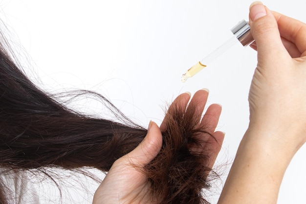 Uma jovem de cabelo comprido e uma pipeta na mão Tratamento e cuidados capilares