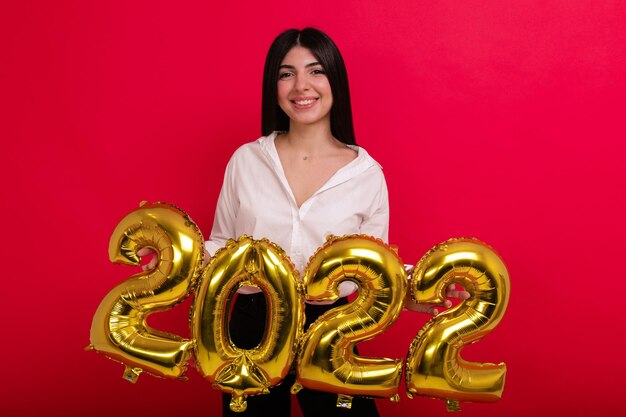 Uma jovem de camisa branca mostra os números do ano novo de 2022