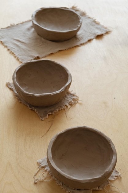 Uma jovem de manga comprida cinza faz um vaso de barro com as próprias mãos em uma oficina de escultura