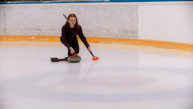 Uma jovem de óculos com cabelo curto jogando curling