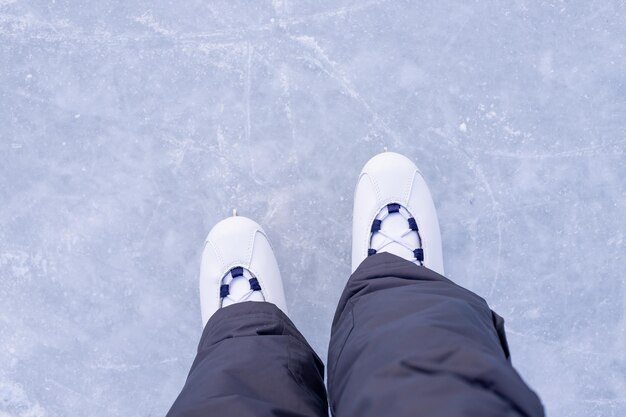 Uma jovem de patins brancos está de pé no gelo pronta para o passeio na pista Treinamento Entretenimento e passatempo de inverno Lazer e estilo de vida Esportes de inverno patinação espaço de cópia