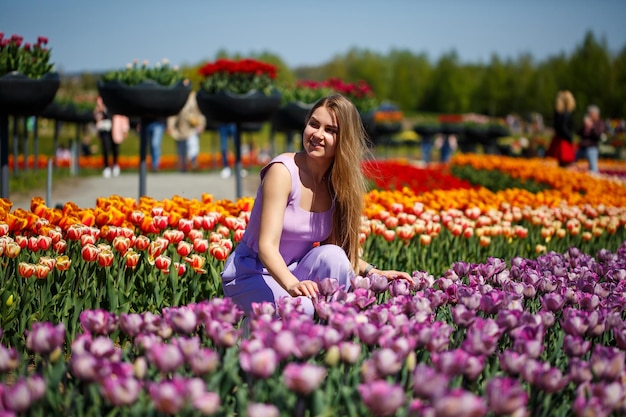 Uma jovem de terno rosa fica em um campo florescente de tulipas Tempo de primavera