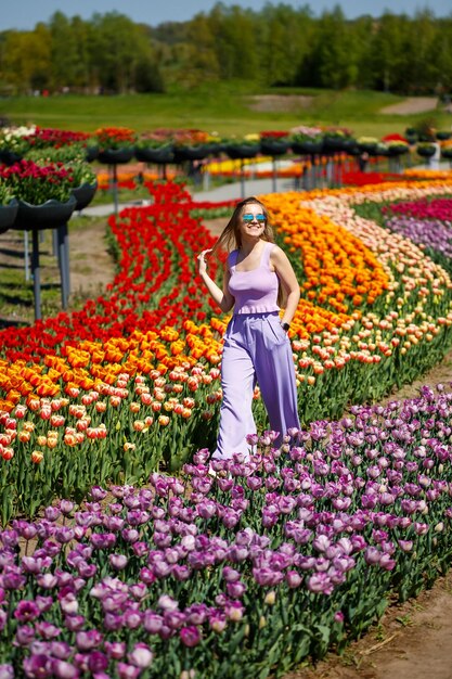 Uma jovem de terno rosa fica em um campo florescente de tulipas Tempo de primavera