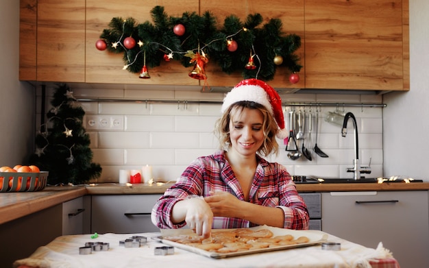 Uma jovem decora um biscoito de natal recém-assado. close-up de doces artesanais de férias. fazendo doces artesanais festivos de natal para presentes